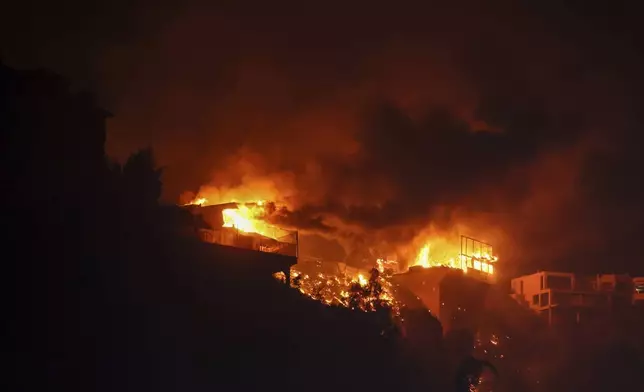 The Palisades Fire burns houses in the hill next to the Getty Villa Wednesday, Jan. 8, 2025 in Pacific Palisades, Calif. (AP Photo/Etienne Laurent)