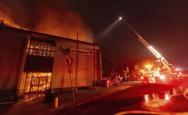 The Eaton Fire burns a Bank Of America branch Wednesday, Jan. 8, 2025 in Altadena, Calif. (AP Photo/Ethan Swope)