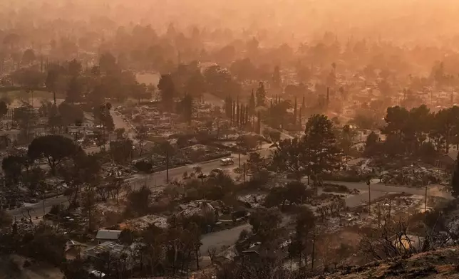 Smoke lingers over a neighborhood devastated by the Eaton Fire, Thursday, Jan. 9, 2025, in Altadena, Calif. (AP Photo/John Locher)