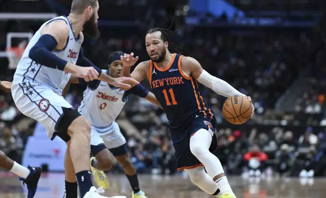 New York Knicks guard Jalen Brunson (11) drives to the basket as Washington Wizards center Jonas Valanciunas, left, defends during the second half of an NBA basketball game, Monday, Dec. 30, 2024, in Washington. (AP Photo/Terrance Williams)