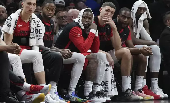 Miami Heat guard Tyler Herro, left, and center Bam Adebayo, far right, watch from the bench during the second half of an NBA basketball game against the Utah Jazz, Saturday, Jan. 4, 2025, in Miami. (AP Photo/Lynne Sladky)