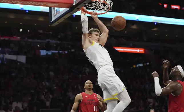 Utah Jazz forward Lauri Markkanen dunks over Miami Heat forward Kesha Johnson (16) and center Bam Adebayo, right, during the second half of an NBA basketball game Saturday, Jan. 4, 2025, in Miami. (AP Photo/Lynne Sladky)