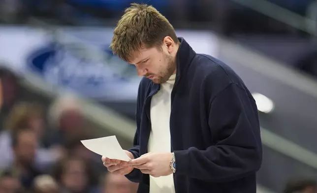 Dallas Mavericks guard Luka Doncic looks over notes during a timeout in the first half of an NBA basketball game against the Denver Nuggets, Sunday, Jan. 12, 2025, in Dallas. (AP Photo/Julio Cortez)