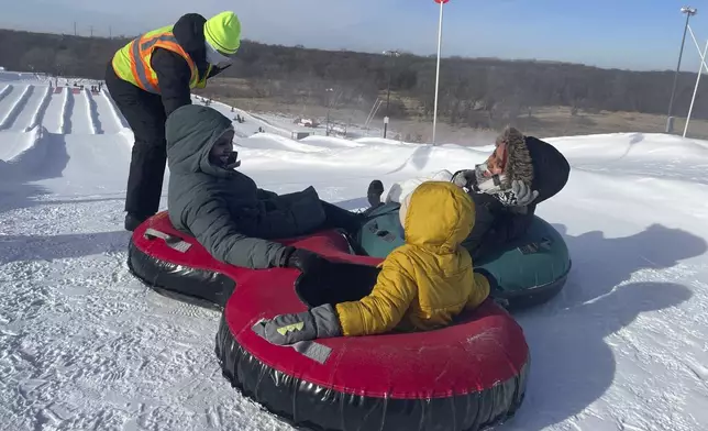 Nasrieen Habib, left, seated, her son, center, and Makiya Amin go snow tubing during an outing organized by the group Habib founded to promote outdoors activities among Muslim women, at Elm Creek Park Reserve in Maple Grove, Minn., on Jan. 4, 2025. (AP Photo/Giovanna Dell'Orto)