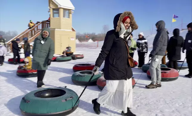 Nasrieen Habib, left, and Makiya Amin pull their snow tubes on top of a hill during an outing organized by the group Habib founded to promote outdoors activities among Muslim women, at Elm Creek Park Reserve in Maple Grove, Minn., on Jan. 4, 2025. (AP Photo/Mark Vancleave)