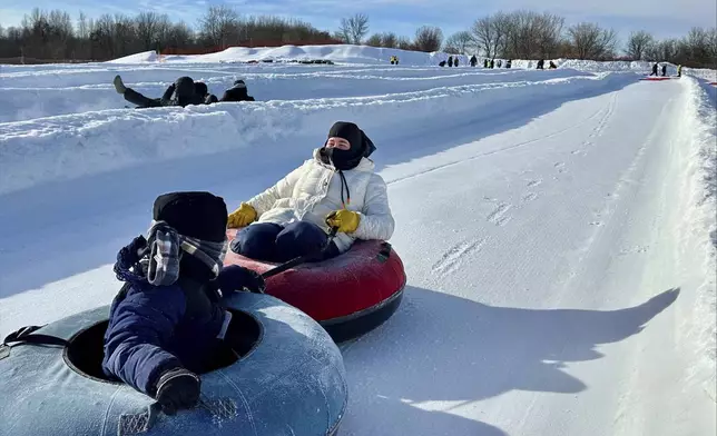 Jorida Latifi and her 7-year-old son ride on snow tubes during an outing organized by a group that promotes outdoors activities for Muslim women at Elm Creek Park Reserve in Maple Grove, Minn., on Jan. 4, 2025. (AP Photo/Mark Vancleave)