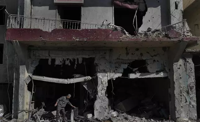 FILE - Ali Haidous, removes the debris from his destroyed butcher shop after he returned with his family to his village of Hanouiyeh, southern Lebanon, on Nov. 28, 2024, following a ceasefire between Israel and Hezbollah. (AP Photo/Hussein Malla, File)