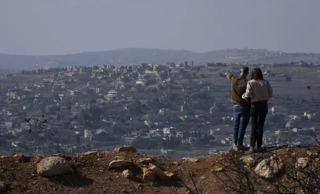 FILE - An Israeli couple can see buildings in southern Lebanon that were damaged during the war from an overlook in northern Israel, on Nov. 30, 2024. (AP Photo/Leo Correa, File)