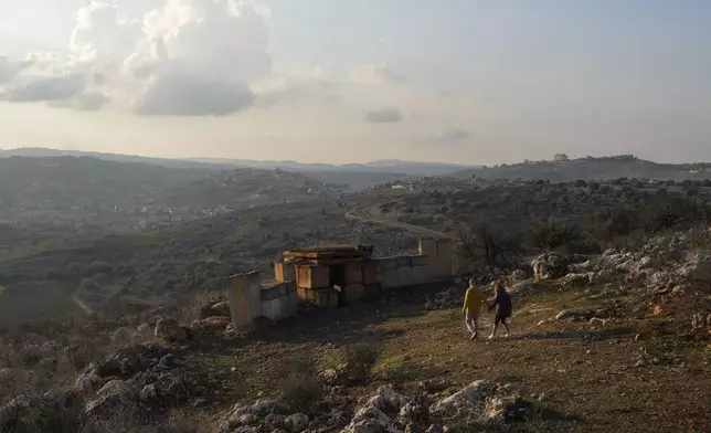 FILE - A couple walks to an Israeli army position near the Lebanese border on Dec. 5, 2024, in northern Israel. (AP Photo/Matias Delacroix, File)