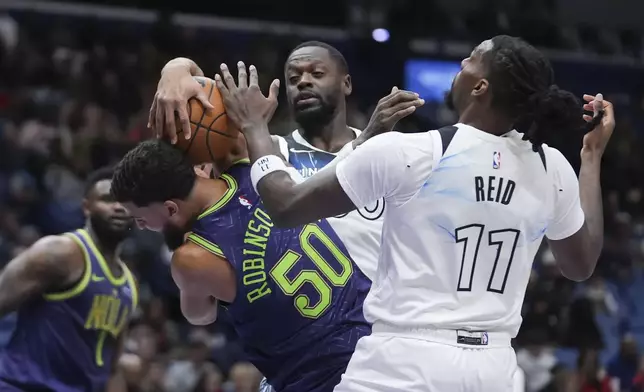 New Orleans Pelicans forward Jeremiah Robinson-Earl (50) battles for a rebound with Minnesota Timberwolves center Naz Reid (11) and forward Julius Randle in the first half of an NBA basketball game in New Orleans, Tuesday, Jan. 7, 2025. (AP Photo/Gerald Herbert)