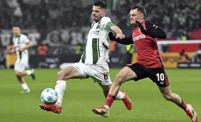 Leverkusen's Florian Wirtz, right, and Gladbach's Julian Weigl fight for the ball during the German Bundesliga soccer match between Bayer Leverkusen and Borussia Moenchengladbach, at the BayArena in Leverkusen, Germany, Saturday, Jan. 18, 2025. (Federico Gambarini/dpa via AP)