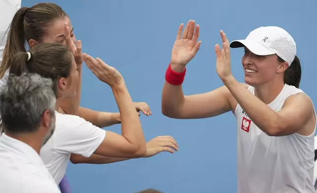 Poland's Iga Swiatek is congratulated by teammates after defeating Czech Republic's Karolina Muchova in their match at the United Cup tennis tournament in Sydney, Australia, Wednesday, Jan. 1, 2025. (AP Photo/Mark Baker)