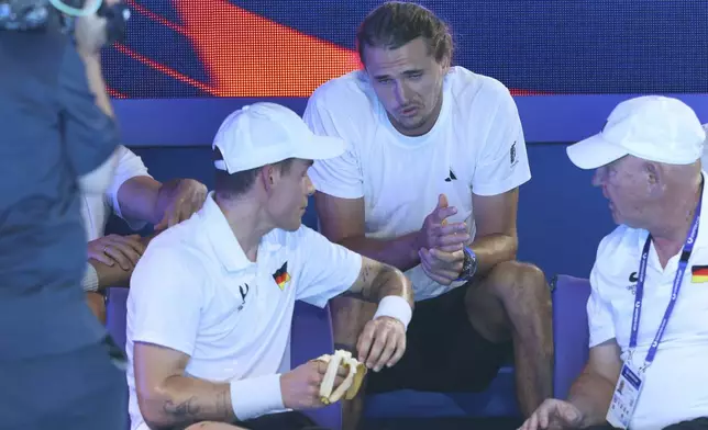 Alexander Zverev of Germany, center, talks to his replacement Daniel Masur, left, during a break in Germany's quarter final match against Alexander Shevchenko, after Zverev pulled out with a bicep injury from the United Cup tennis match in Perth, Australia, Wednesday, Jan. 1, 2025. (AP Photo/Trevor Collens)