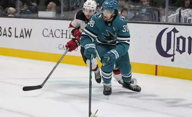 San Jose Sharks defenseman Mario Ferraro (38) skates with the puck against New Jersey Devils center Nico Hischier during the second period of an NHL hockey game in San Jose, Calif., Saturday, Jan. 4, 2025. (AP Photo/Jeff Chiu)