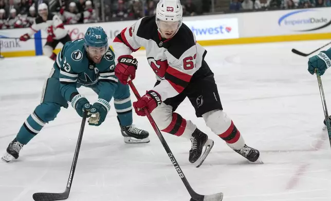 New Jersey Devils left wing Jesper Bratt, middle, skates with the puck against San Jose Sharks right wing Barclay Goodrow (23) during the second period of an NHL hockey game in San Jose, Calif., Saturday, Jan. 4, 2025. (AP Photo/Jeff Chiu)