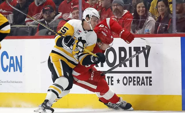 Detroit Red Wings right wing Jonatan Berggren, right, is shoved into the boards by Pittsburgh Penguins center Noel Acciari (55) during the first period of an NHL hockey game Tuesday, Dec. 31, 2024, in Detroit. (AP Photo/Duane Burleson)