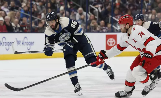 Columbus Blue Jackets' Kirill Marchenko, left, shoots the puck as Carolina Hurricanes' Jaccob Slavin defends during the second period of an NHL hockey game Tuesday, Dec. 31, 2024, in Columbus, Ohio. (AP Photo/Jay LaPrete)