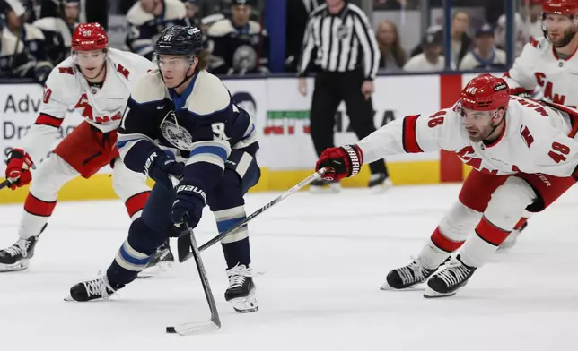 Columbus Blue Jackets' Kent Johnson, left, skates past Carolina Hurricanes' Jordan Martinook during the second period of an NHL hockey game, Tuesday, Dec. 31, 2024, in Columbus, Ohio. (AP Photo/Jay LaPrete)