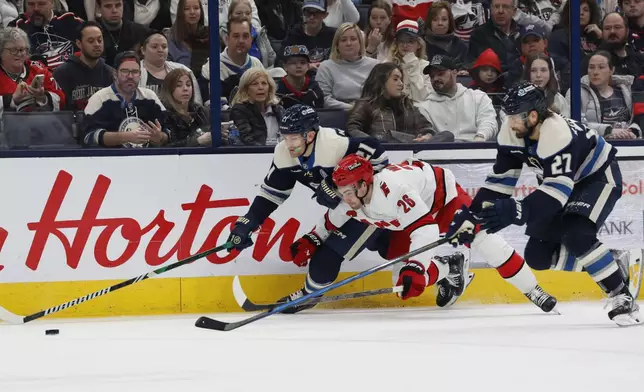 Columbus Blue Jackets' James van Riemsdyk, left, Zachary Aston-Reese, right, and Carolina Hurricanes' Sean Walker chase the puck during the second period of an NHL hockey game, Tuesday, Dec. 31, 2024, in Columbus, Ohio. (AP Photo/Jay LaPrete)