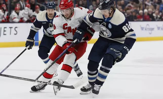 Carolina Hurricanes' Sean Walker, left, and Columbus Blue Jackets' Mikael Pyyhtia chase the puck during the first period of an NHL hockey game Tuesday, Dec. 31, 2024, in Columbus, Ohio. (AP Photo/Jay LaPrete)