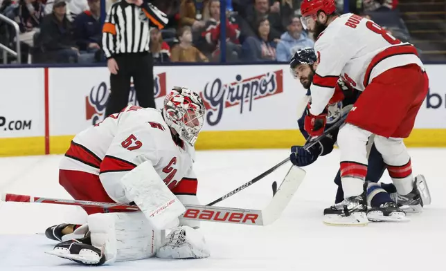 Carolina Hurricanes' Pyotr Kochetkov, left, covers the puck as teammate Brent Burns, right, and Columbus Blue Jackets' Kirill Marchenko fight for position during the second period of an NHL hockey game Tuesday, Dec. 31, 2024, in Columbus, Ohio. (AP Photo/Jay LaPrete)