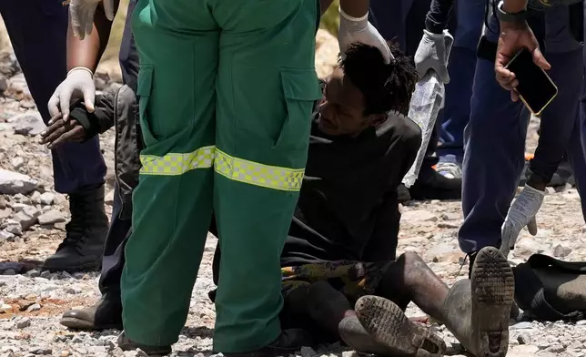 A miner is assisted by rescue workers after he was rescued from below ground in an abandoned gold mine in Stilfontein, South Africa, Tuesday, Jan. 14, 2025. (AP Photo/Themba Hadebe)