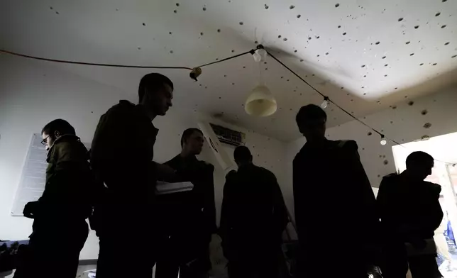 Israeli soldiers stand in a bullet-ridden house during a tour for army personnel to observe the damage caused by the Oct. 7 Hamas onslaught at Kibbutz Kfar Aza, near the Israeli-Gaza border, in Israel, Thursday, Jan. 2, 2025. (AP Photo/Matias Delacroix)