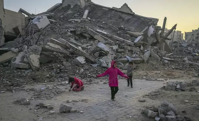 Palestinian children play next to a building destroyed by Israeli army strikes in the central Gaza Strip town of Khan Younis, Wednesday, Jan. 1, 2025. (AP Photo/Abdel Kareem Hana)