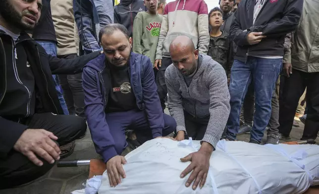 Palestinians prepare the body for the funeral of a man killed during an Israeli army strike in Deir al-Balah in the central Gaza Strip, Thursday Jan. 2, 2025. The strike killed at least eight men members of local committees that help secure aid convoys, according to the Al-Aqsa Martyrs Hospital, which received the bodies.(AP Photo/Abdel Kareem Hana)