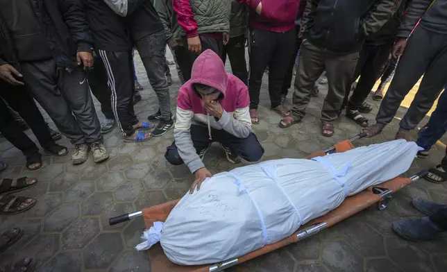 A man mourns over the body of a Palestinian man killed during an Israeli army strike in Deir al-Balah in the central Gaza Strip, Thursday Jan. 2, 2025. The strike killed at least eight men members of local committees that help secure aid convoys, according to the Al-Aqsa Martyrs Hospital, which received the bodies.(AP Photo/Abdel Kareem Hana)