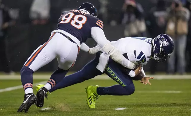 Seattle Seahawks quarterback Geno Smith, right, is sacked by Chicago Bears defensive end Montez Sweat during the first half of an NFL football game, Thursday, Dec. 26, 2024, in Chicago. (AP Photo/Erin Hooley)