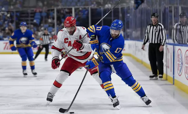 Buffalo Sabres left wing Jason Zucker, right, looks to control the puck against Carolina Hurricanes left wing Jordan Martinook during the first period of an NHL hockey game in Buffalo, N.Y., Wednesday, Jan. 15, 2025. (AP Photo/Adrian Kraus)