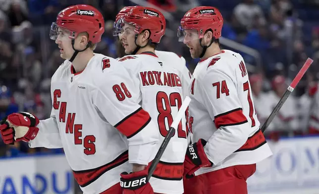 Carolina Hurricanes defenseman Jaccob Slavin, right, celebrates with centers Martin Necas, left, and Jesperi Kotkaniemi after scoring during the third period of an NHL hockey game against the Buffalo Sabres in Buffalo, N.Y., Wednesday, Jan. 15, 2025. (AP Photo/Adrian Kraus)