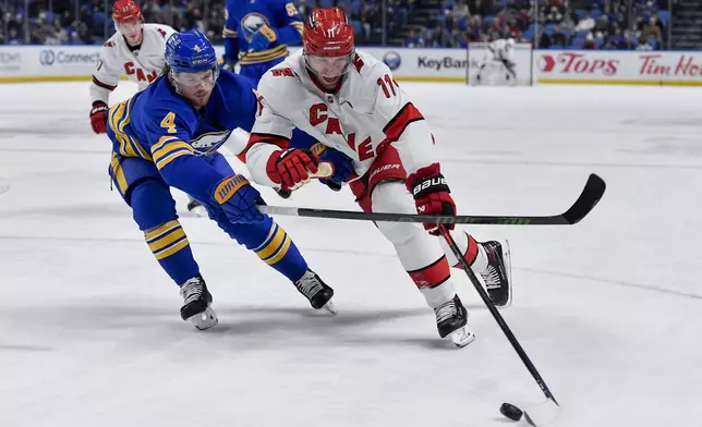 Carolina Hurricanes center Jordan Staal, right, shields the puck from Buffalo Sabres defenseman Bowen Byram (4) during the first period of an NHL hockey game in Buffalo, N.Y., Wednesday, Jan. 15, 2025. (AP Photo/Adrian Kraus)
