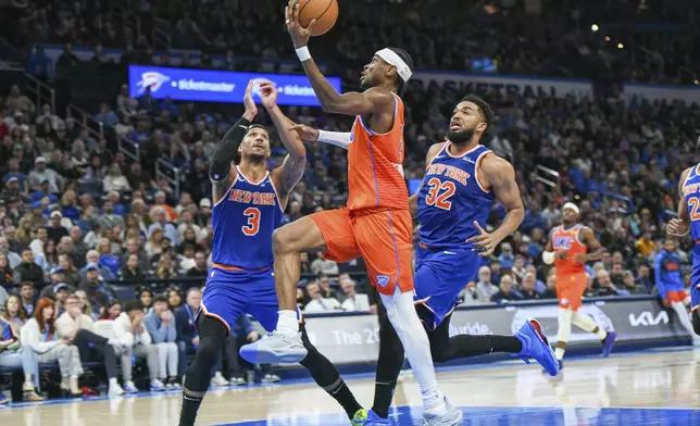 Oklahoma City Thunder guard Shai Gilgeous-Alexander, middle, shoots in front of New York Knicks guard Josh Hart, left, and center Karl-Anthony Towns, right, during the second half of an NBA basketball game, Friday, Jan 3, 2025, in Oklahoma City. (AP Photo/Kyle Phillips)