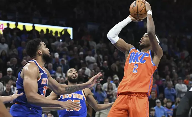 Oklahoma City Thunder guard Shai Gilgeous-Alexander, right, shoots over New York Knicks center Karl-Anthony Towns, left, and forward Mikal Bridges, middle, during the second half of an NBA basketball game, Friday, Jan 3, 2025, in Oklahoma City. (AP Photo/Kyle Phillips)