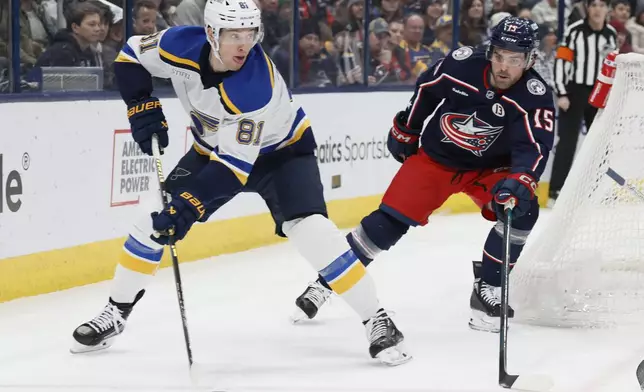 St. Louis Blues' Dylan Holloway, left, looks for an open pass as Columbus Blue Jackets' Dante Fabbro defends during the first period of an NHL hockey game Saturday, Jan. 4, 2025, in Columbus, Ohio. (AP Photo/Jay LaPrete)