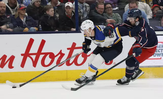 St. Louis Blues' Dylan Holloway, left, keeps the puck away from Columbus Blue Jackets' Dante Fabbro, right, during the third period of an NHL hockey game Saturday, Jan. 4, 2025, in Columbus, Ohio. (AP Photo/Jay LaPrete)