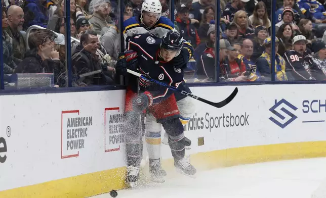 Columbus Blue Jackets' Cole Sillinger, front, keeps the puck away from St. Louis Blues' Philip Broberg during the second period of an NHL hockey game Saturday, Jan. 4, 2025, in Columbus, Ohio. (AP Photo/Jay LaPrete)