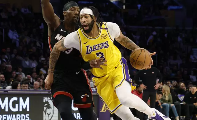 Los Angeles Lakers forward Anthony Davis is pressured by Miami Heat center Bam Adebayo as hr drives to the basket during the first half of an NBA basketball game Wednesday, Jan. 15, 2025, in Los Angeles. (AP Photo/Kevork Djansezian)