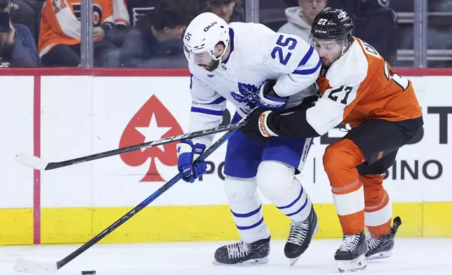 Philadelphia Flyers' Noah Cates, right, tries to get the puck from Toronto Maple Leafs' Conor Timmins during the second period of an NHL hockey game, Tuesday, Jan. 7, 2025, in Philadelphia. (AP Photo/Matt Slocum)