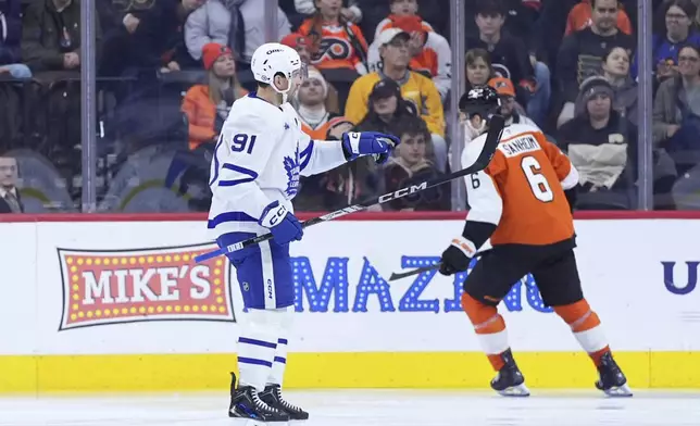 Toronto Maple Leafs' John Tavares, left, reacts past Philadelphia Flyers' Travis Sanheim after scoring a goal during the second period of an NHL hockey game, Tuesday, Jan. 7, 2025, in Philadelphia. (AP Photo/Matt Slocum)