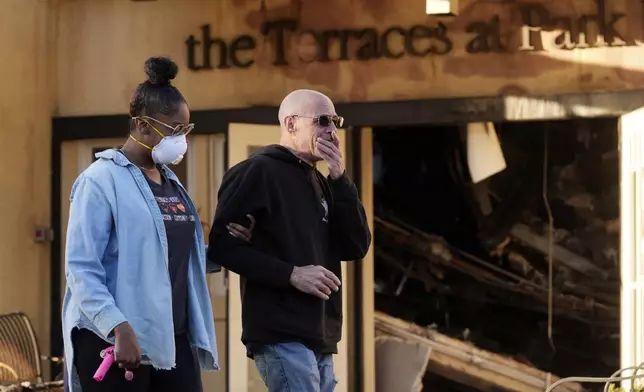 Sam Baum, right, community relations director at the Terraces at Park Marino assisted living facility, is consoled by Activities Director Lashawna Thompson after seeing fire damage to the facility from the Eaton Fire on Monday, Jan. 13, 2025, in Pasadena, Calif. (AP Photo/Chris Pizzello)