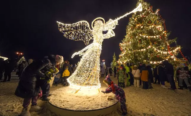 Children play at a square illuminated for the holidays near the Naval Cathedral of Saint Nicholas on Orthodox Christmas Eve in Kronstadt on the outskirts of St. Petersburg, Russia, Monday, Jan. 6, 2025. (AP Photo/Dmitri Lovetsky)