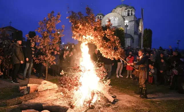 Christian Orthodox believers, who follow the Julian calendar and celebrate Christmas on Jan. 7, burn dried oak branches, the Yule log symbol for the Orthodox Christmas Eve, in front of St. Luke church in Belgrade, Serbia, Monday, Jan. 6, 2025. (AP Photo/Darko Vojinovic)