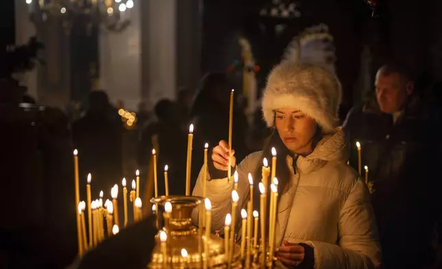 A Lithuanian Orthodox worshipper lights candles before the liturgy on Orthodox Christmas Eve in the Orthodox Church of the Holy Spirit in Vilnius, Lithuania, Monday, Jan. 6, 2025. (AP Photo/Mindaugas Kulbis)