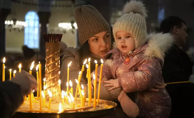 A woman talks with her child prior to the Orthodox Christmas service in the Naval Cathedral of Saint Nicholas in the city of Kronstadt, outside St. Petersburg, Russia, Monday, Jan. 6, 2025. (AP Photo/Dmitri Lovetsky)