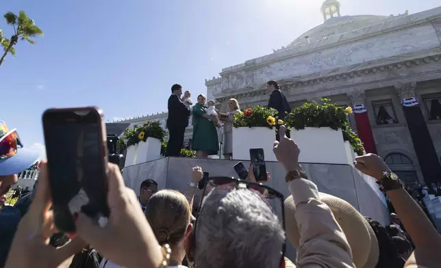 Jenniffer Gonzalez Colon and her husband hold their children on a podium outside the Capitol during Colon's swearing-in ceremony as governor in San Juan, Puerto Rico, Thursday, Jan. 2, 2025. (AP Photo/Alejandro Granadillo)