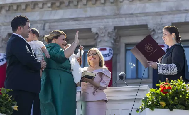 Jenniffer Gonzalez Colon is sworn in as governor by Supreme Court Chief Justice Maite Oronoz Rodriguez outside the Capitol in San Juan, Puerto Rico, Thursday, Jan. 2, 2025. At left his Gonzalez's husband Jose Yovin Vargas. (AP Photo/Alejandro Granadillo)