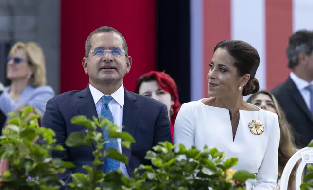 Outgoing Governor Pedro Pierluisi sits with his wife Fabiola Ansotegui during the inauguration ceremony of the new Governor Jenniffer Gonzalez Colon outside the Capitol in San Juan, Puerto Rico. Thursday, Jan. 2, 2025. (AP Photo/Alejandro Granadillo)